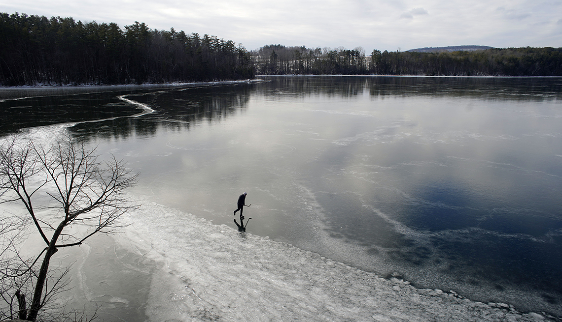 item 17 of Gallery image - a person holding a hockey stick skates on a frozen lake surrounded by bare trees