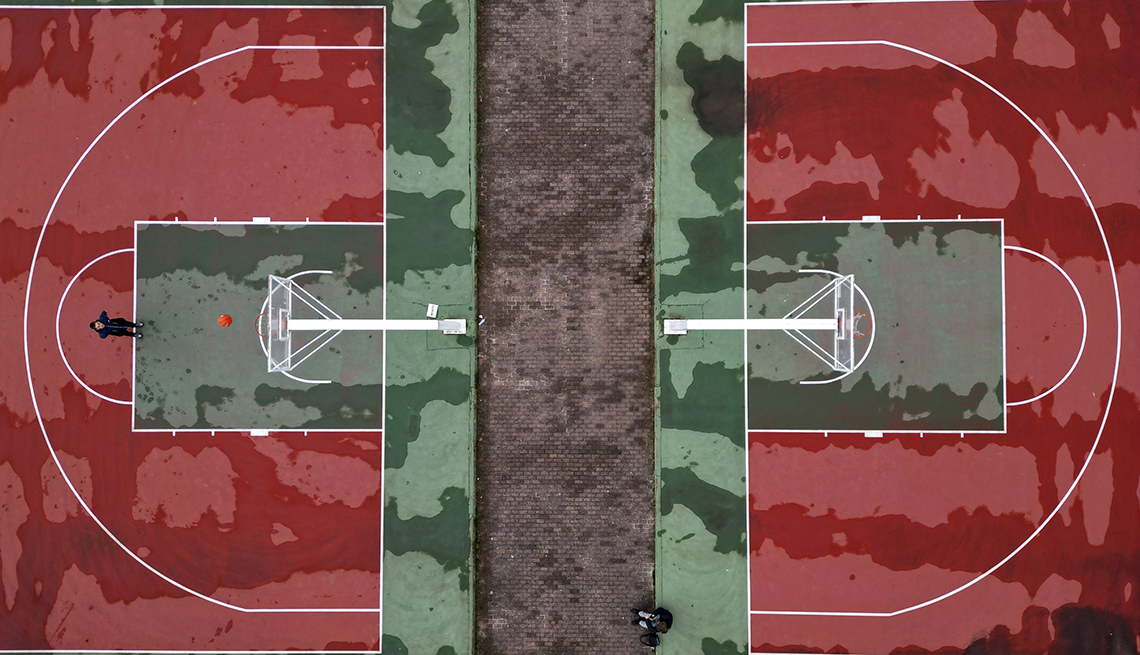 item 6 of Gallery image - aerial view of a green and red basketball court reminiscent of a watermelon, where one person shoots a basketball and another sits checking their phone