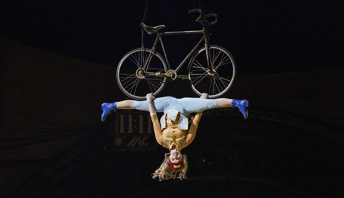 item 15 of Gallery image - acrobat in a full split hangs from a bicycle