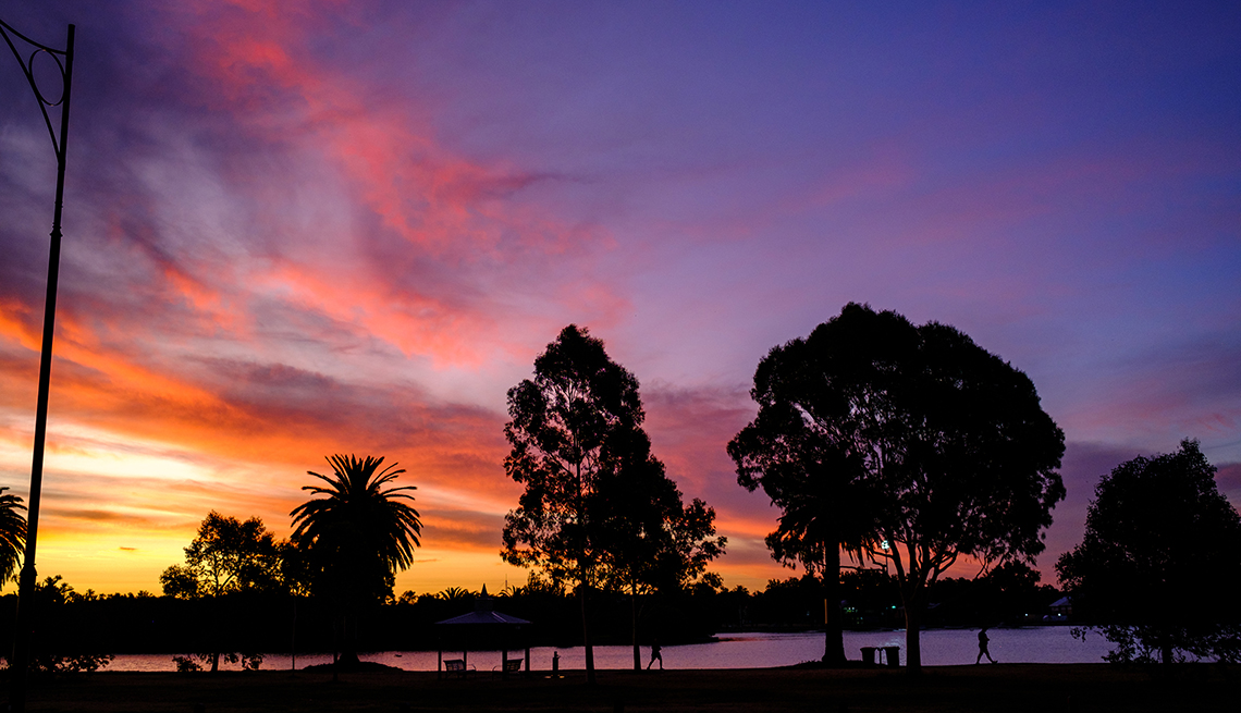item 3 of Gallery image - trees and people in silhouette in front of a river reflecting colorful clouds at sunset 