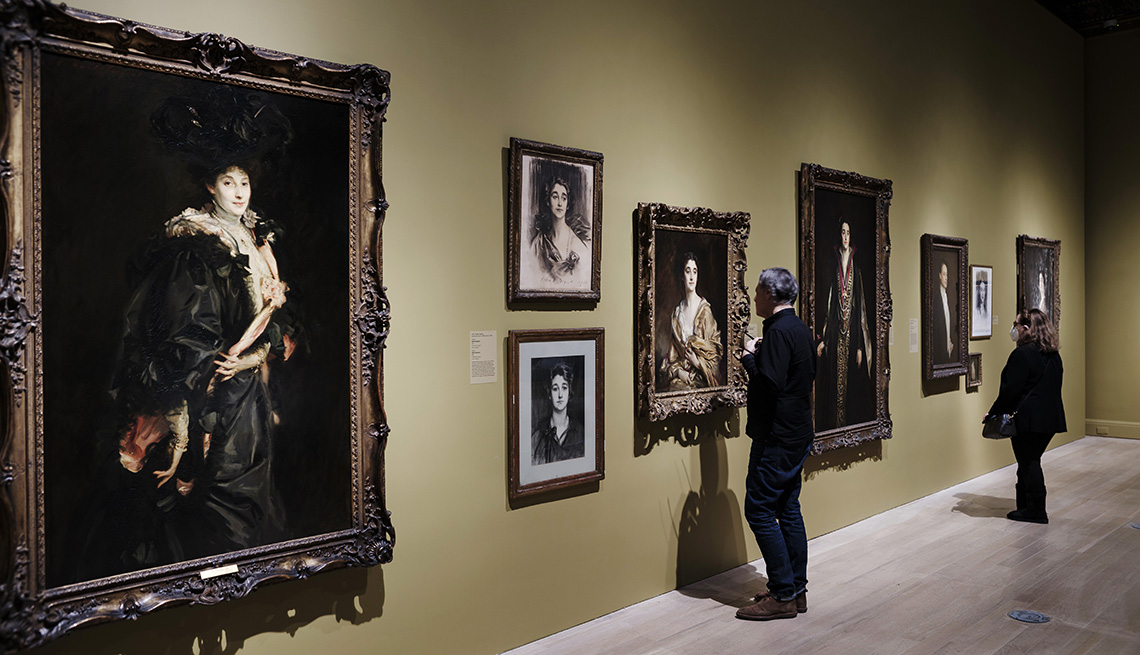 item 9 of Gallery image - two people look closely at portraits of the sassoon family by John Singer Sargent on a wall of an exhibit