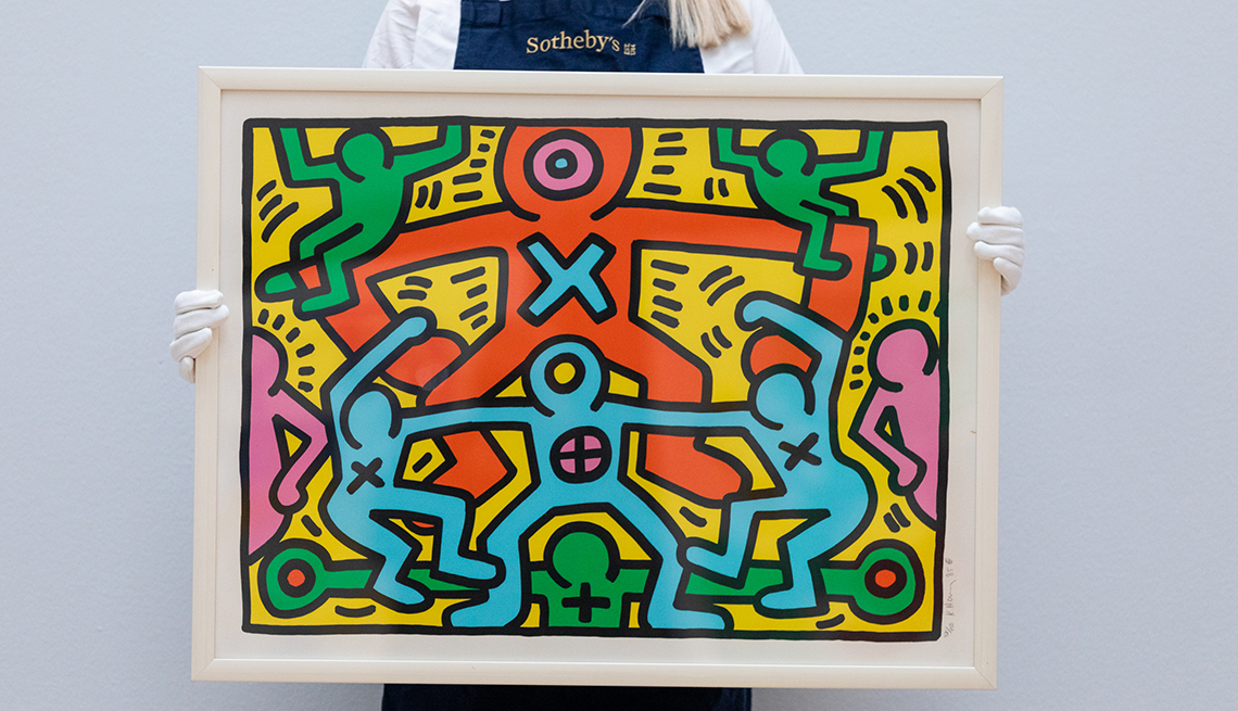 item 17 of Gallery image - a keith haring painting is held up by someone wearing white gloves