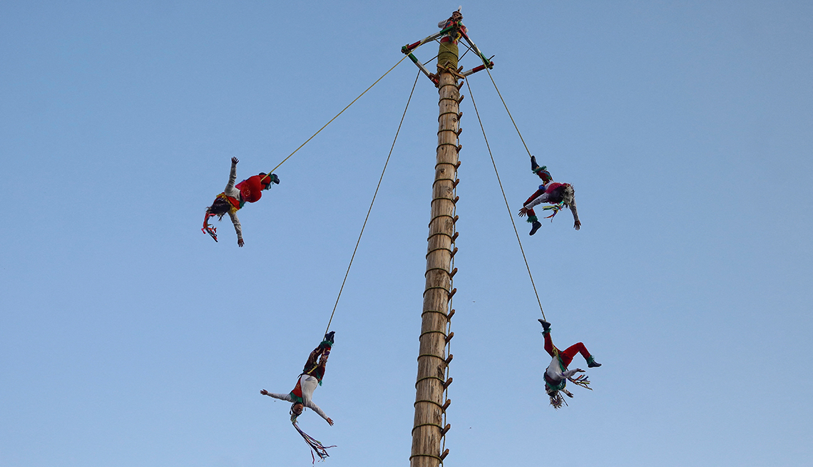 item 10 of Gallery image - four women in acrobatic poses hanging from ropes off a tall pole against a blue sky
