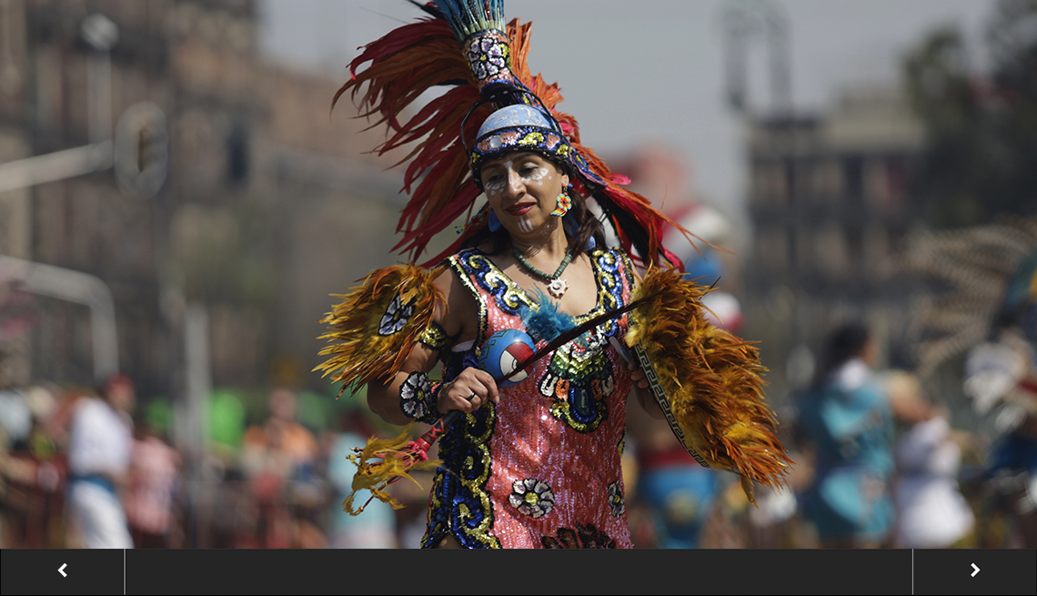 dancer dressed in colorful aztec costume with people and buildings blurred in the background, with slideshow overlay