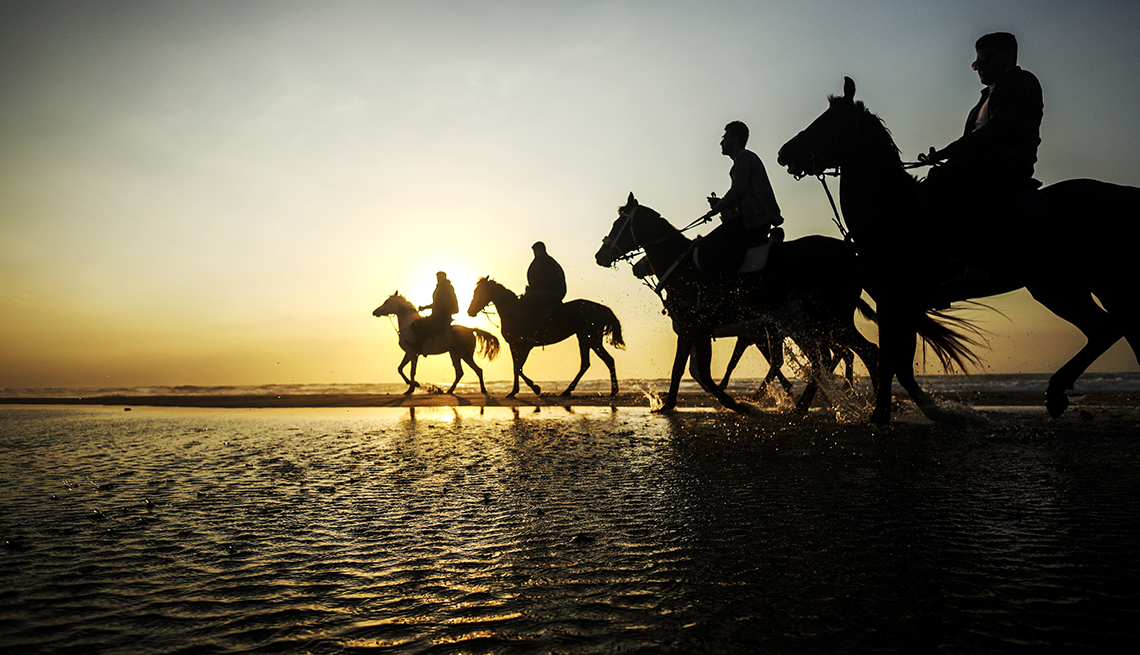 item 10 of Gallery image - four horses with riders in silhouette on a beach at sunset