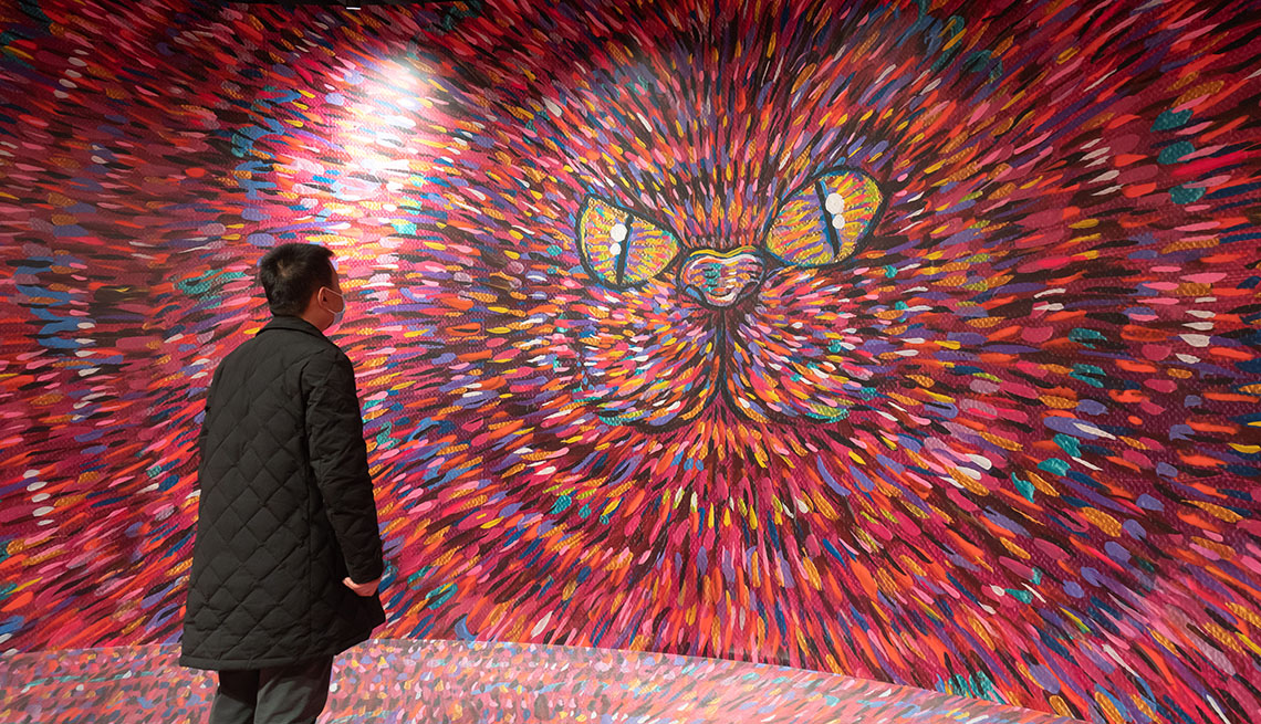 item 9 of Gallery image - a man looks at a large colorful painting depicting a cats face