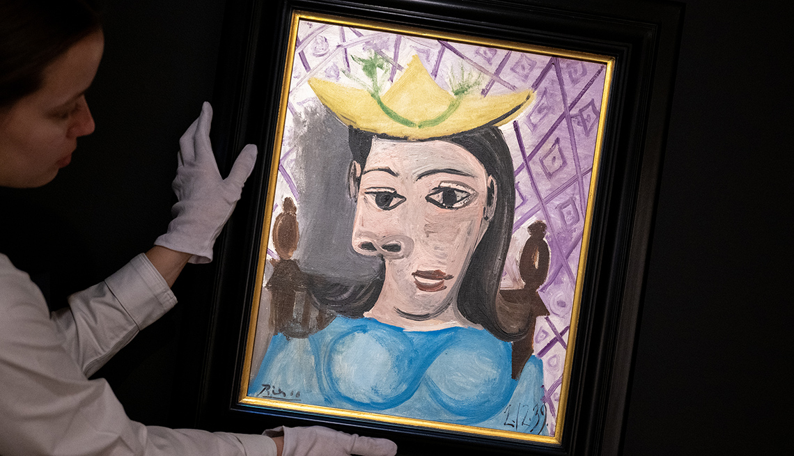 item 13 of Gallery image - an art handler wearing white gloves holds pablo picasso's femme au chapeau jaune
