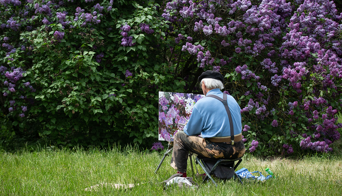 item 5 of Gallery image - a man is seen from behind painting the blooming lilac bushes in front of him