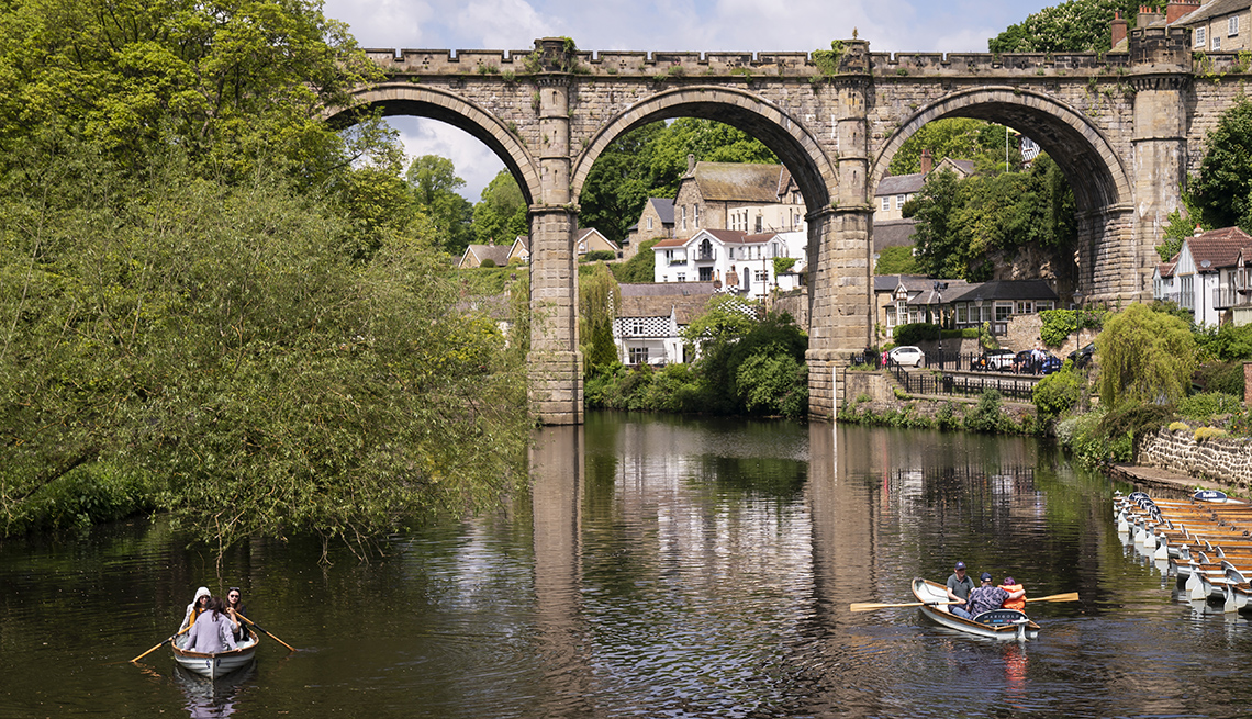 item 11 of Gallery image - two boats are being rowed near a viaduct through which low buildings are visible