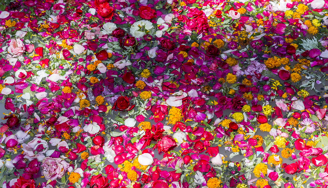 item 6 of Gallery image - flowers, coconuts and other offerings float in a mass of red, pink, white, yellow and green on water that is barely visible underneath