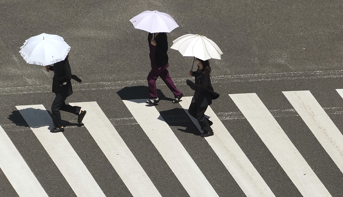 People under parasols cross a street in the Ginza district in Tokyo.