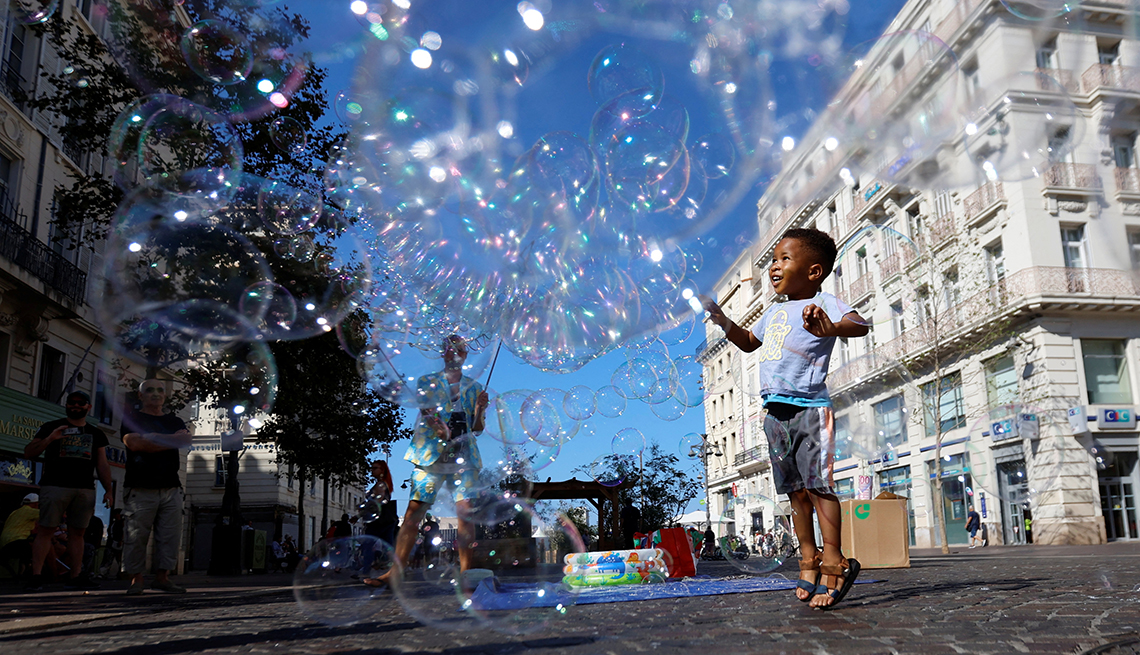 item 5 of Gallery image - A child plays with bubbles from a street performer at the Old Port of Marseille, France.