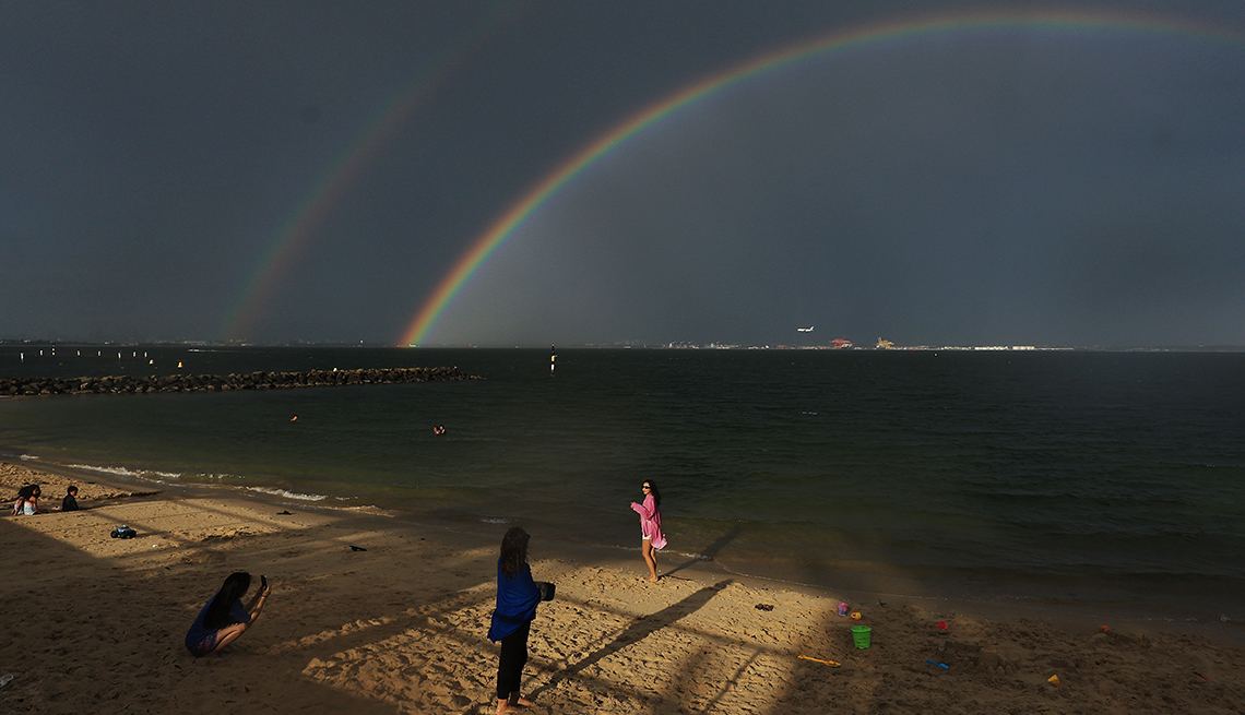 item 2 of Gallery image - A girl poses for a photograph as a double rainbow appears over Botany Bay, Sydney.
