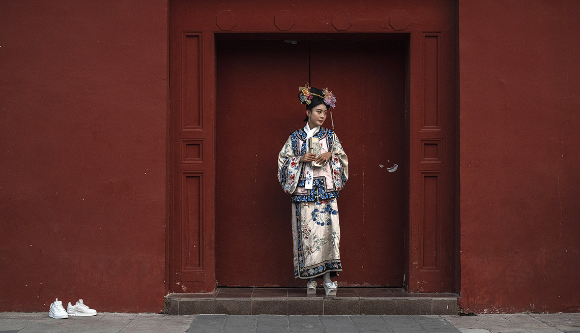 item 7 of Gallery image - A woman wearing a traditional Hanfu costume stands in a doorway near the Forbidden City in Beijing.