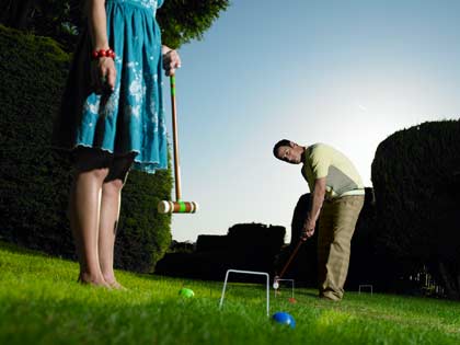 man and young woman playing croquet