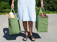 woman with a filled reusable grocery bag in each hand