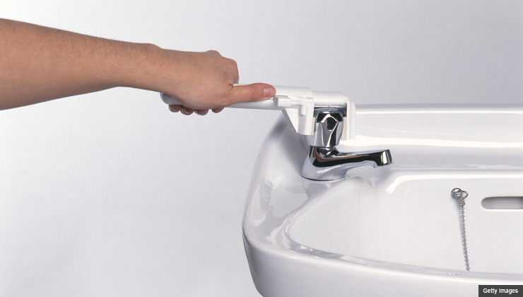 Hand using plastic lever on bathroom basin tap, close-up