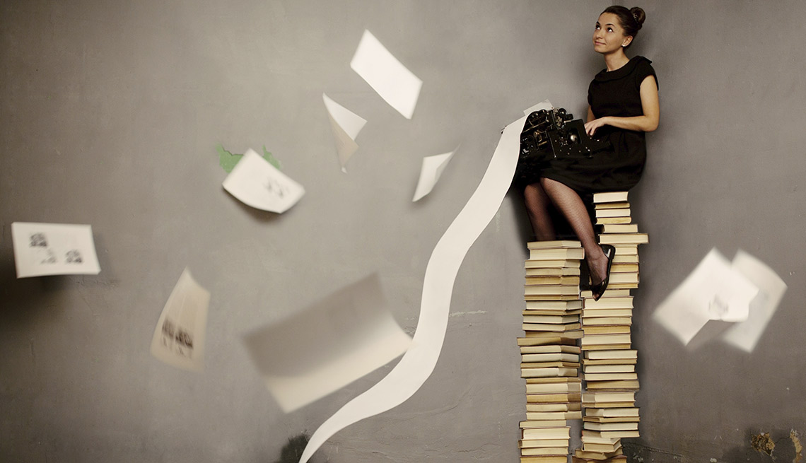 Mujer sentada en una columna de libros apilados - Cómo auto pubiclar un libro usando la tecnología.