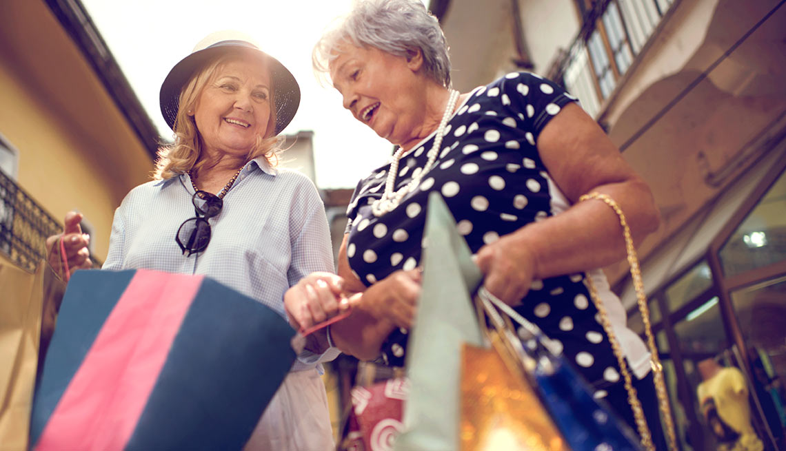 Dos mujeres con bolsas de compras en un centro comercial - Empezar a gastar y dejar de ahorrar en la jubilación