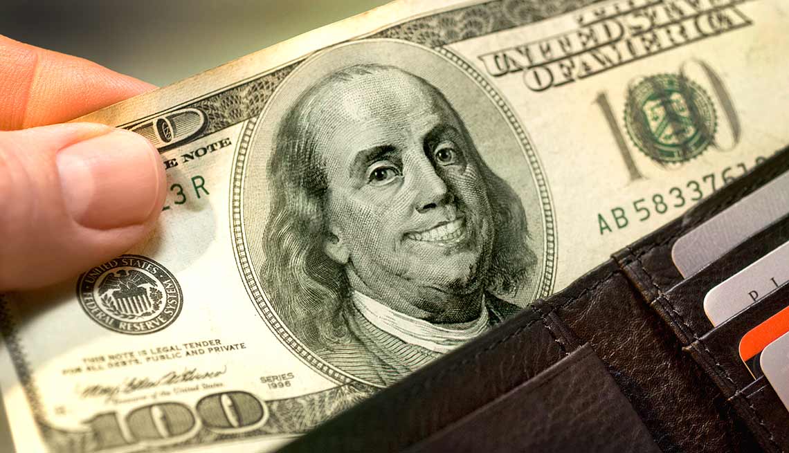Billete de 100 dólares que una mano saca de una billetera - Quiz del coeficiente intelectual financiero
