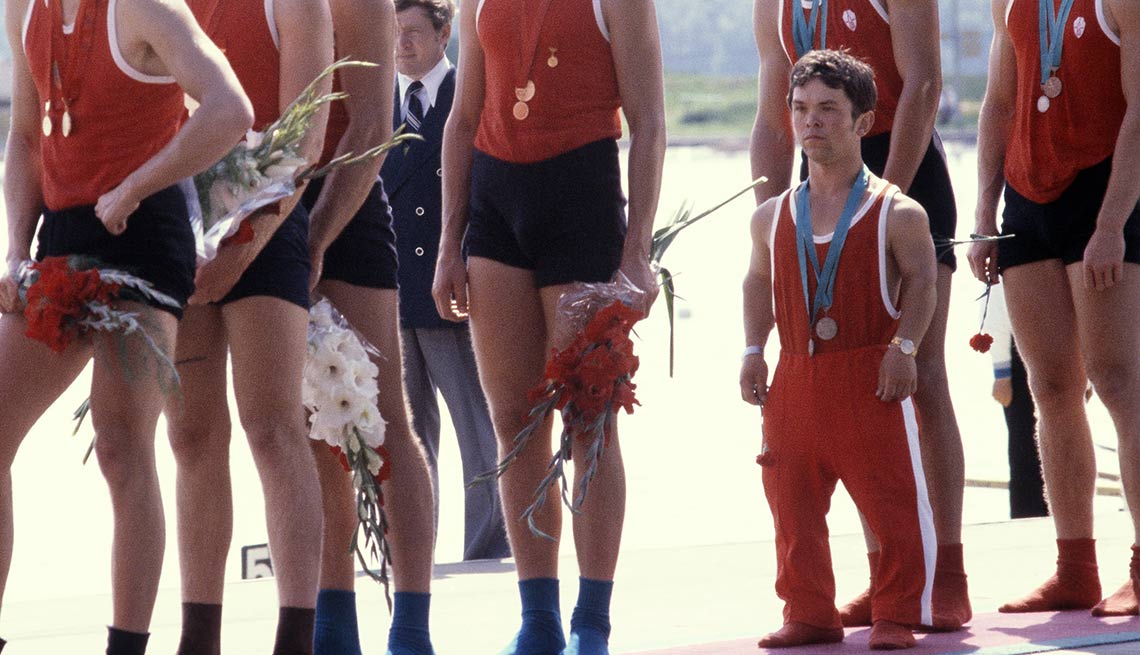 item 8 of Gallery image - Hombre pequeño con traje de atletismo al lado de las piernas de hombres altos - Becas universitarias inusuales