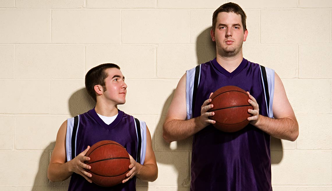 Dos jóvenes con balones y uniformes de baloncesto. Uno es más alto que otro - Becas universitarias inusuales
