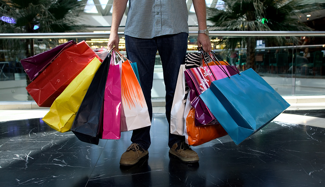 Hombre sosteniendo bolsas de compras de diferentes tiendas