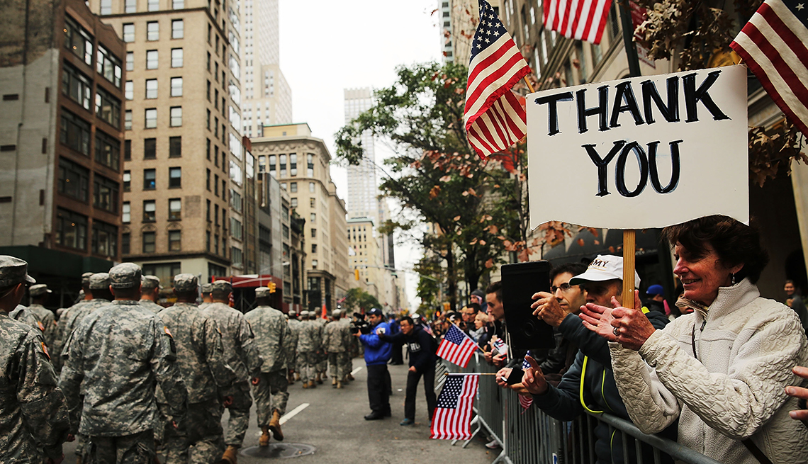 Una mujer sostiene un cartel que dice gracias en inglés durante un desfile de veteranos