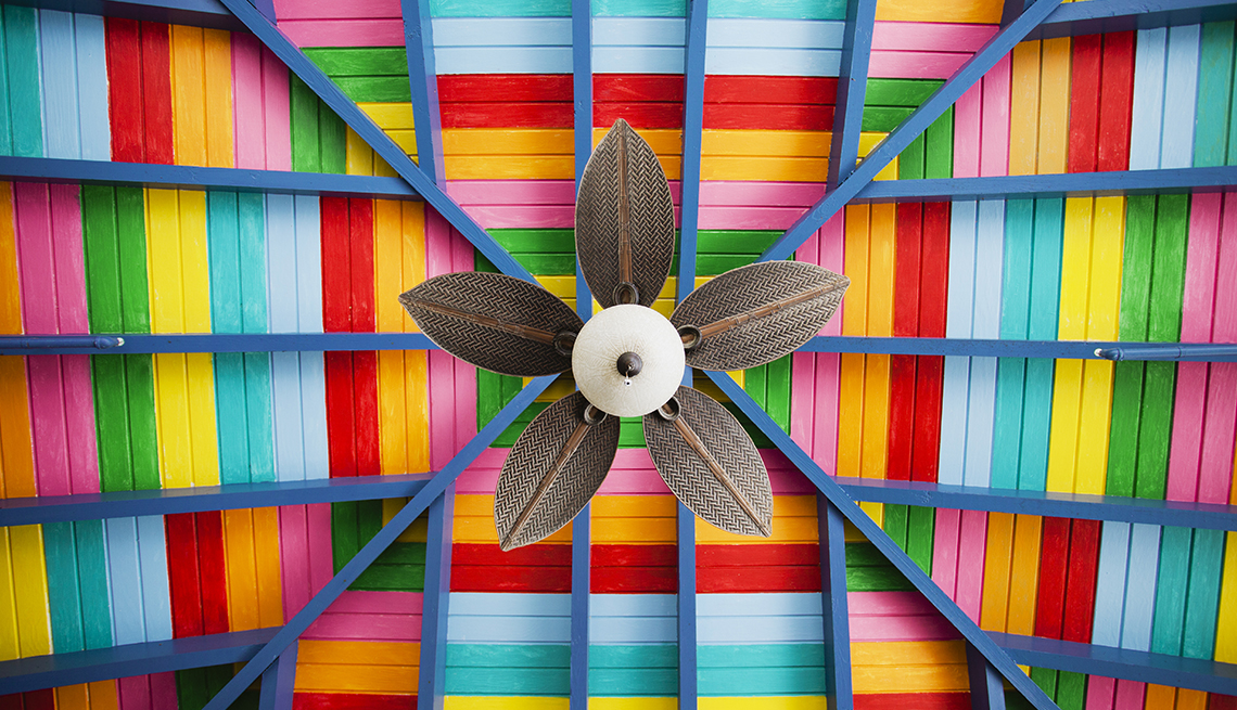 looking up at petal-shaped fan on multi-coloured ceiling