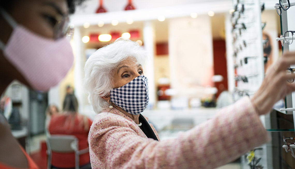 Mujer viendo lentes recetados en una tienda mientras usa la mascarilla.