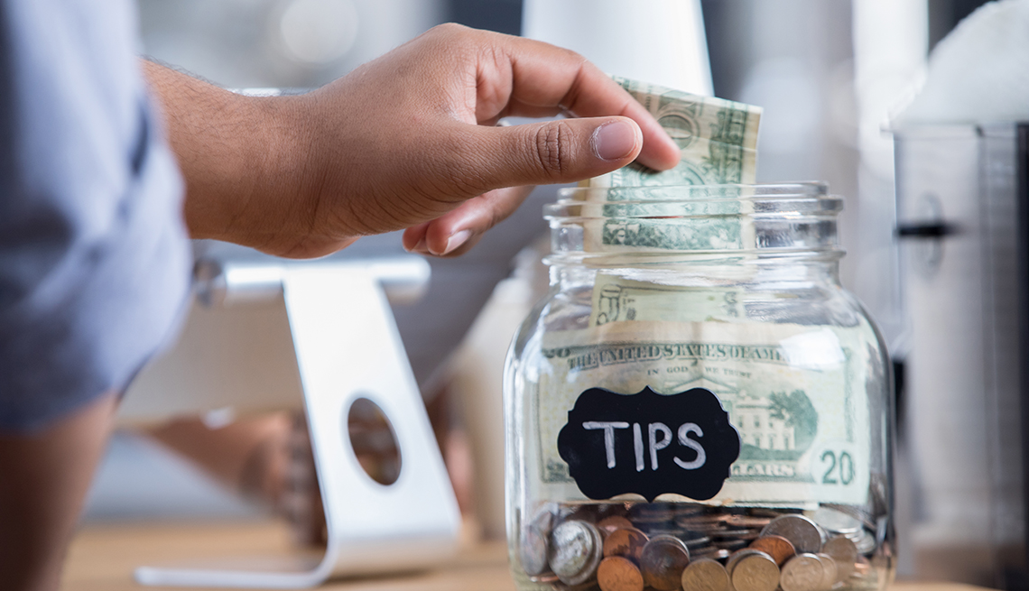 a person puts money into a tip jar