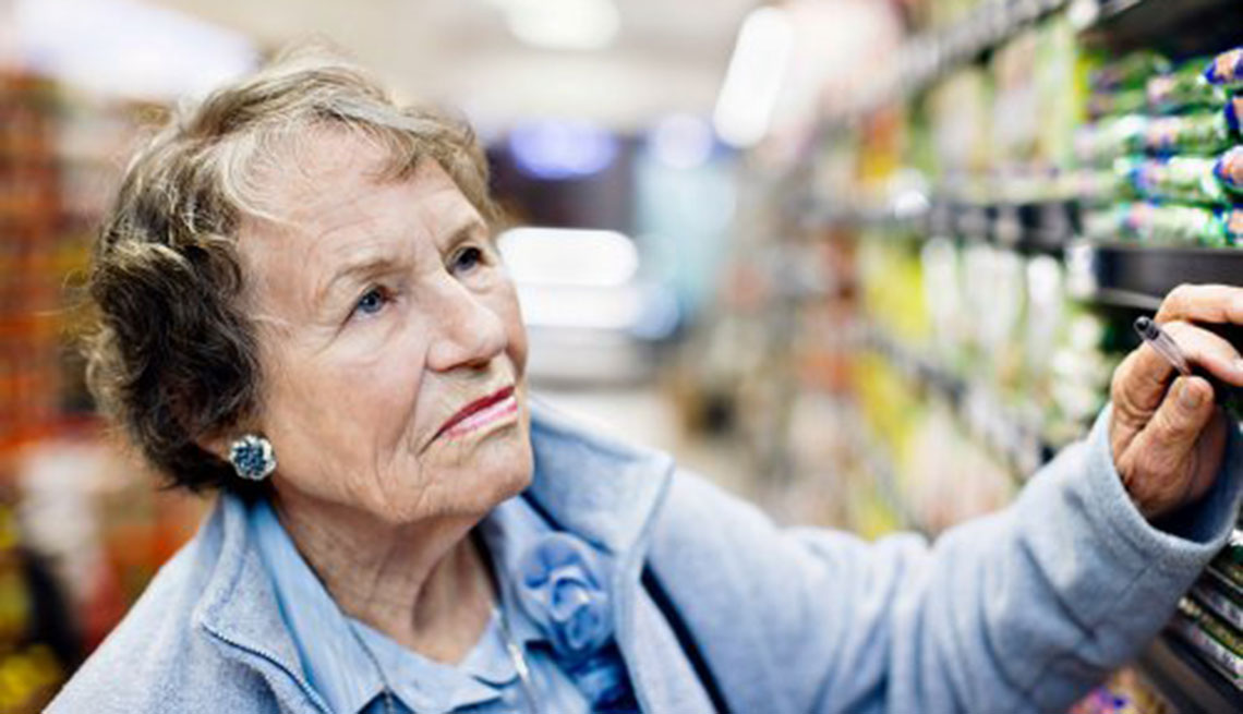 Mujer mayor mirando los precios de los productos en un anaquel de un supermercado