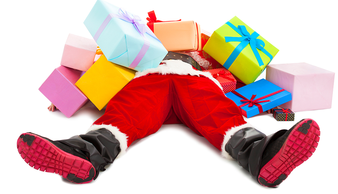 Papa Noel acostado con varios regalos encima de su cuerpo