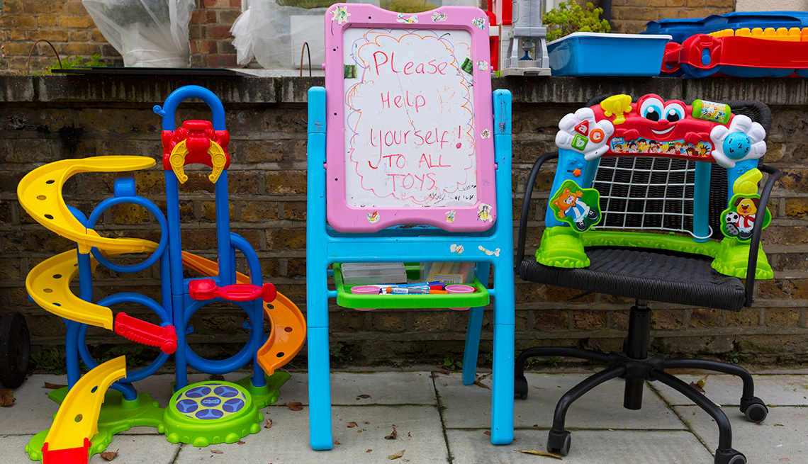 A bunch of unwanted childrens' toys and games left on the curb with a sign that says to help yourself.