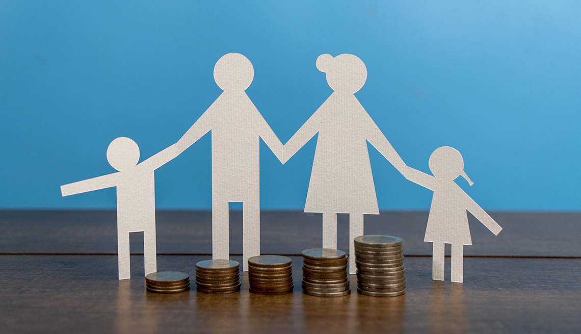 a paper cut out family with coins on a table with a blue background