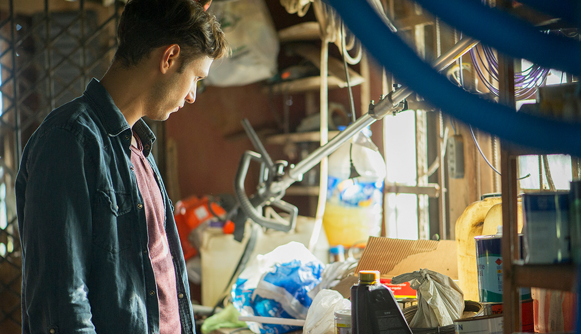 Man searching through a cluttered attic of miscellaneous household goods