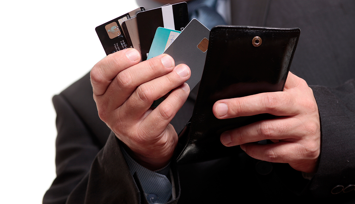 Manos de un hombre sosteniendo tarjetas de crédito sacadas de su billetera. Solo quédate con las mejores