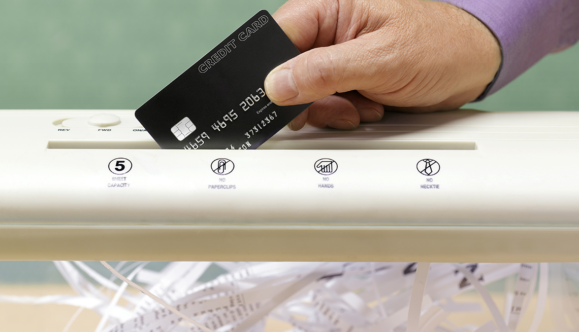 Mano sosteniendo una tarjeta de crédito en una máquina trituradora de papel - Errores comunes con las tarjetas de crédito