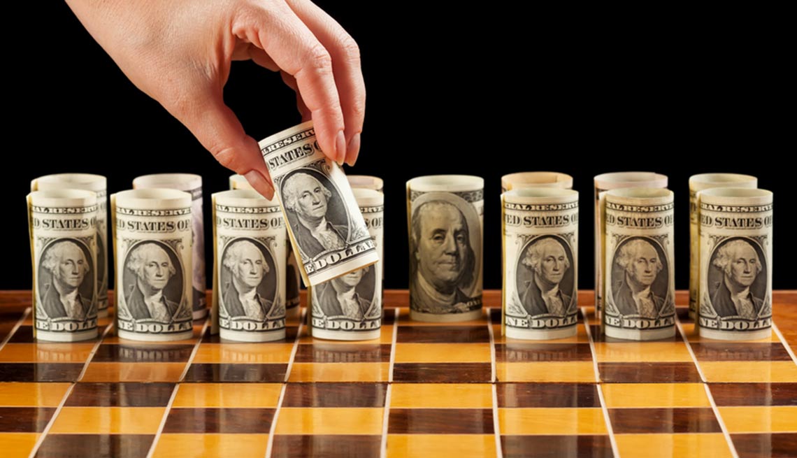 Tablero de ajedrez con billetes de dólar enrollados como piezas de juego - Dónde invertir tu dinero