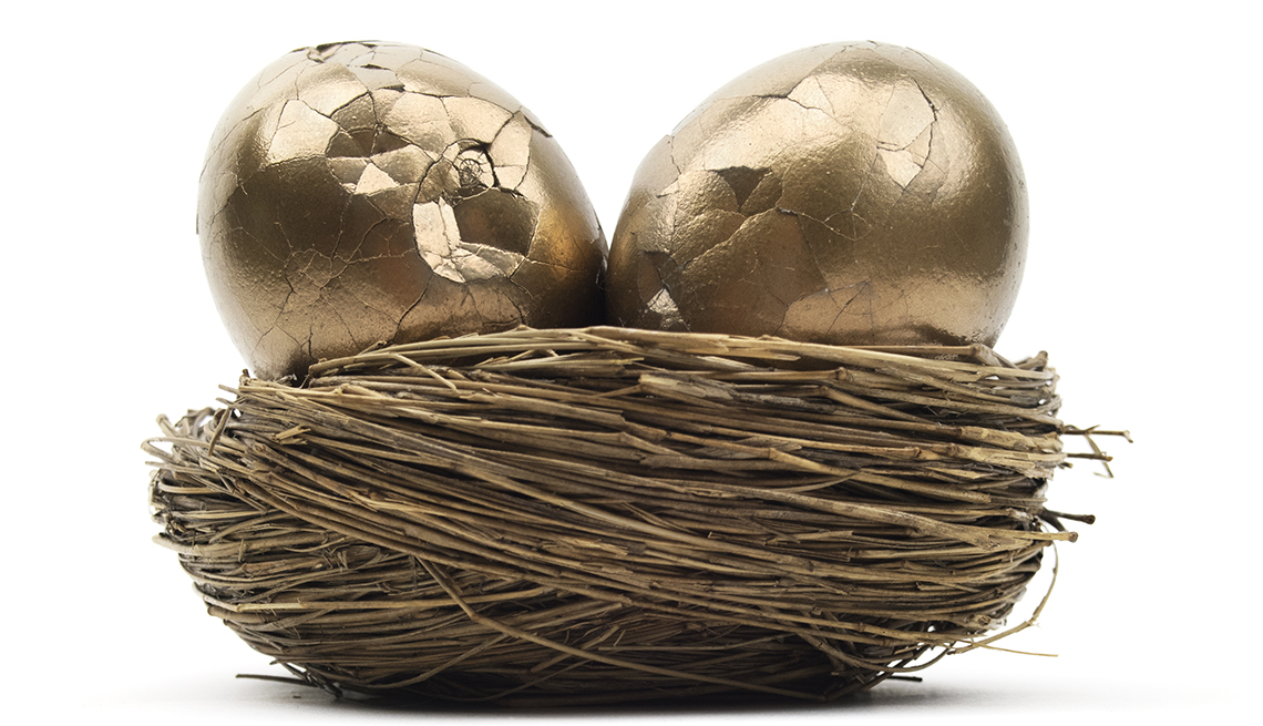 Dos huevos de oro con la cáscara partida encima de un nido.