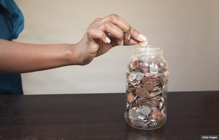 Woman putting coin in savings jar.