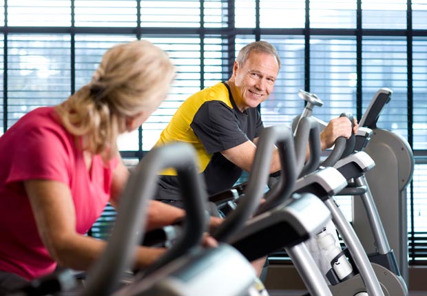 Man and woman riding bikes in health club (Juice Images/Alamy)