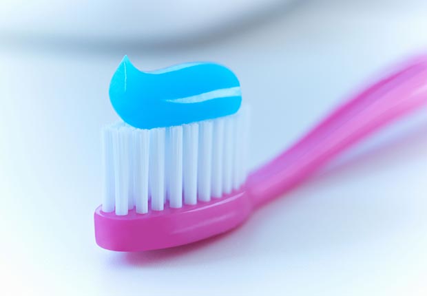 Purple toothbrush with toothpaste. (Adrian Gaultier/Alamy)