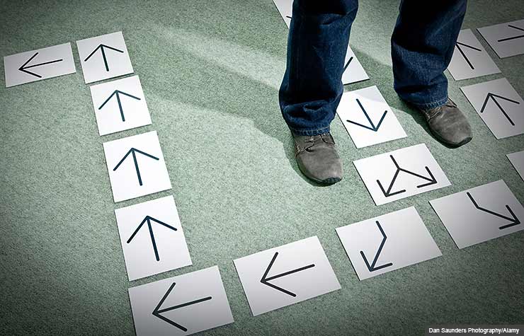 Man's feet and direction arrows, Choosing the Safest Investment Path (Dan Saunders Photography/Alamy)