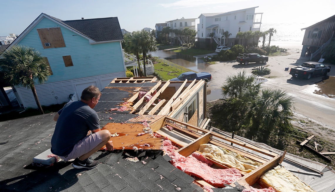 Hombre reparando el techo de una casa después del paso de los huracanes.