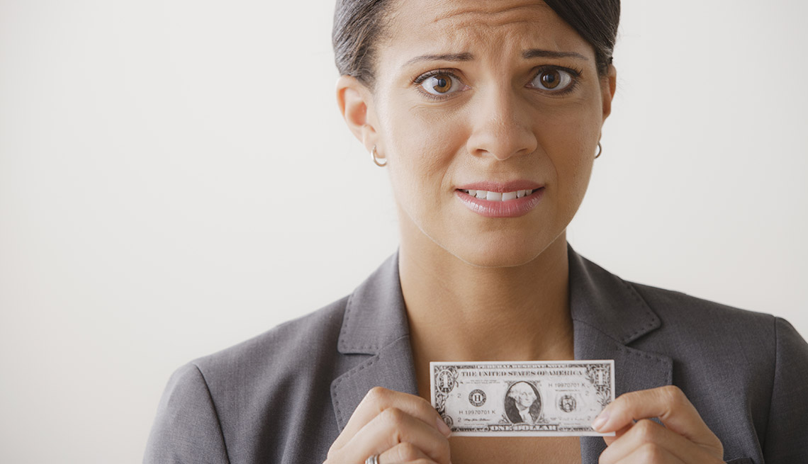 Mujer con cara de angustia y sosteniendo mini billete de un dólar