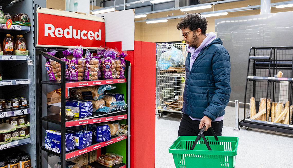Hombre con una canasta mira una sección de productos rebajados en un supermercado