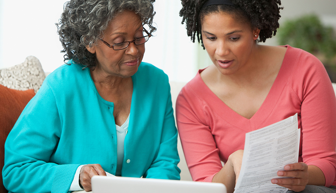 Mother and daughter looking at paperwork. Protect your parents from scams.