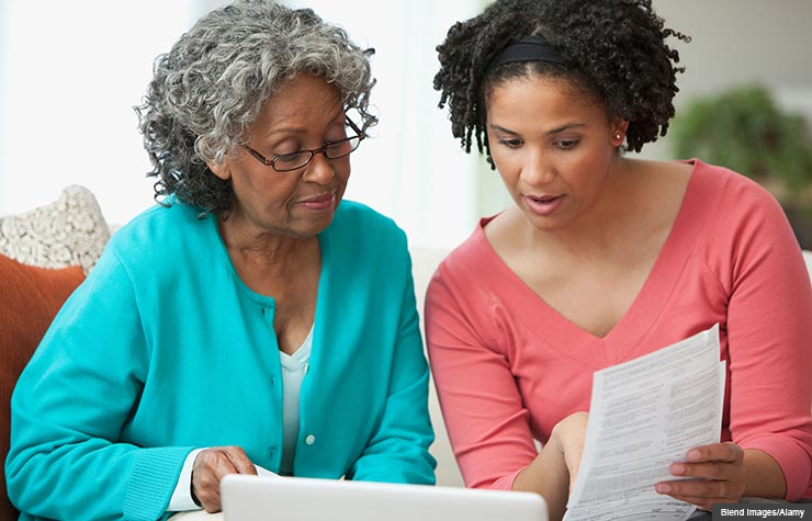 Mother and daughter looking at paperwork. Protect your parents from scams. (Blend Images/Alamy)