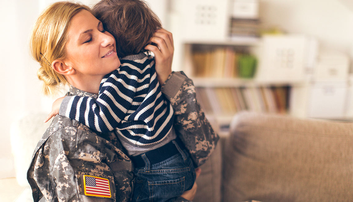 Mujer soldado abrazando a un niñito